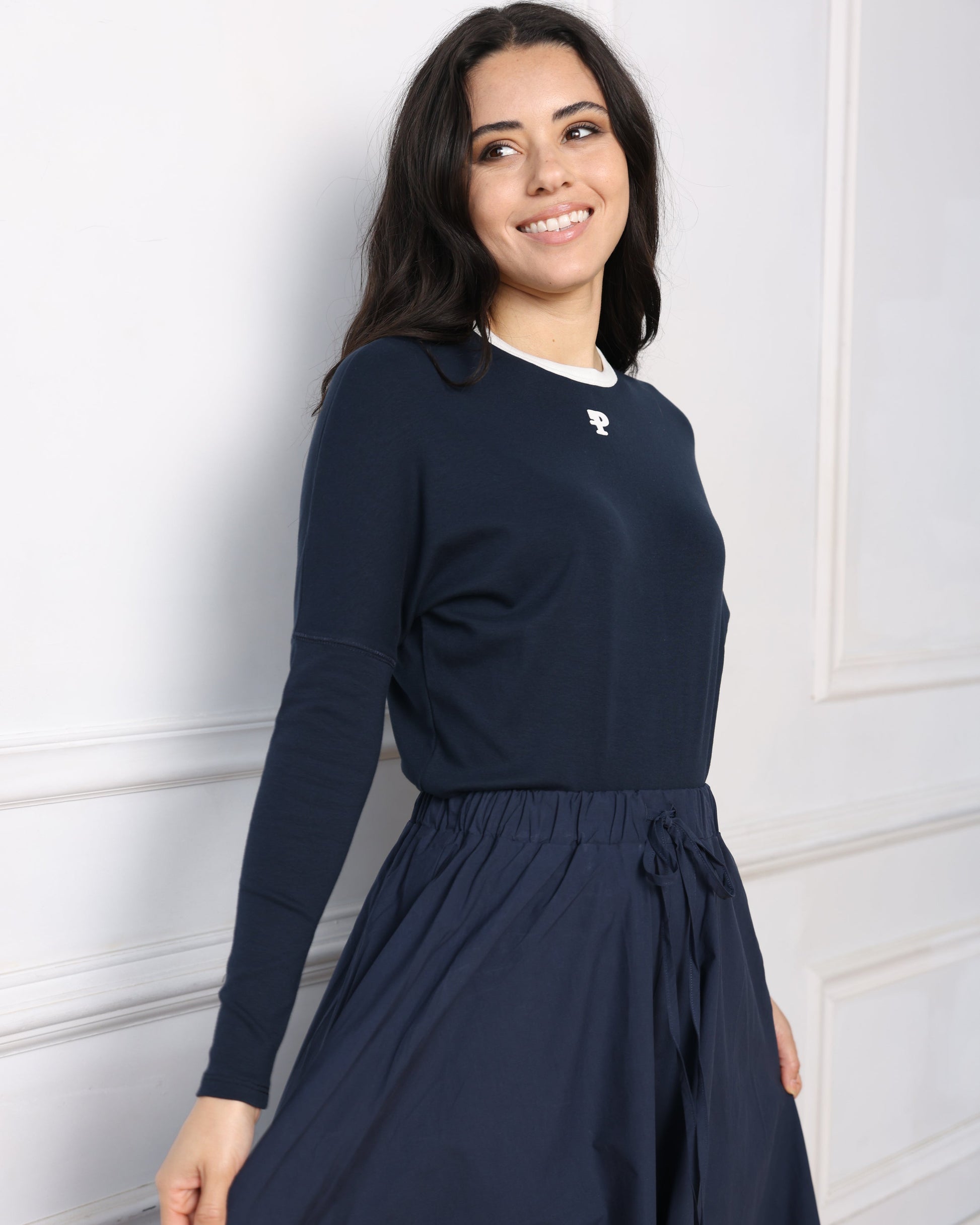 Woman wearing a navy blue dress with a white collar against a white background