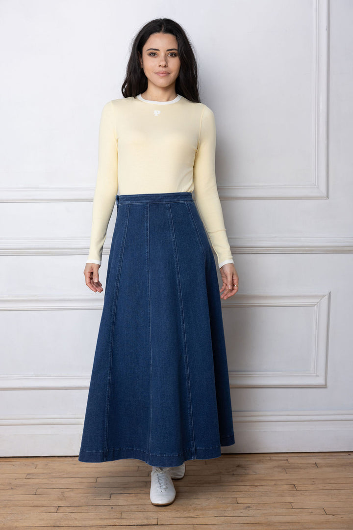 Woman wearing yellow long sleeve Tshirt and denim paneled skirt. 