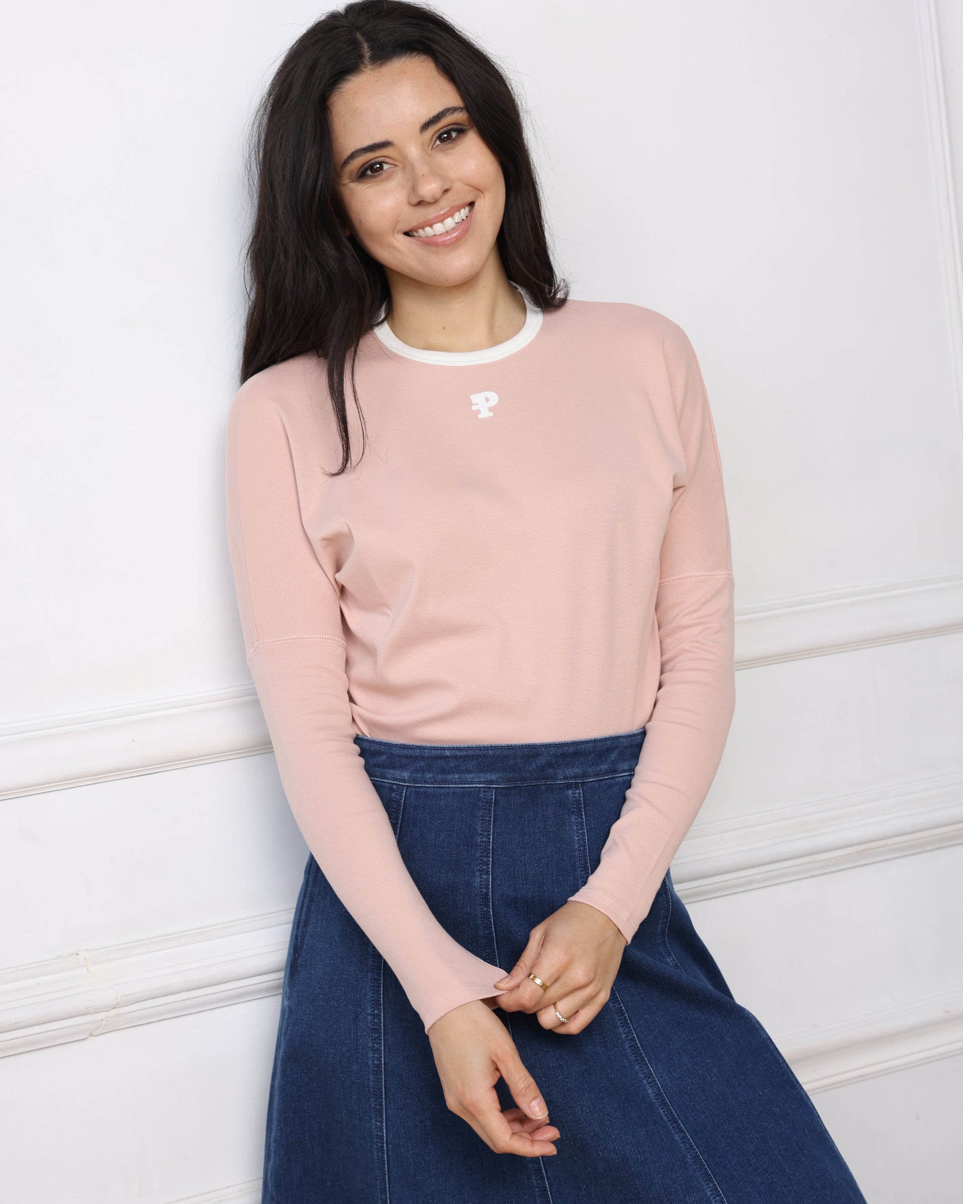 Woman wearing a pink sweatshirt with a logo on a white floor