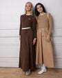 two models wearing maxi skirts and matching tops standing against a white wall.