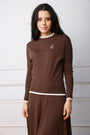 Woman wearing a brown long-sleeve top and skirt with a white collar against a light background
