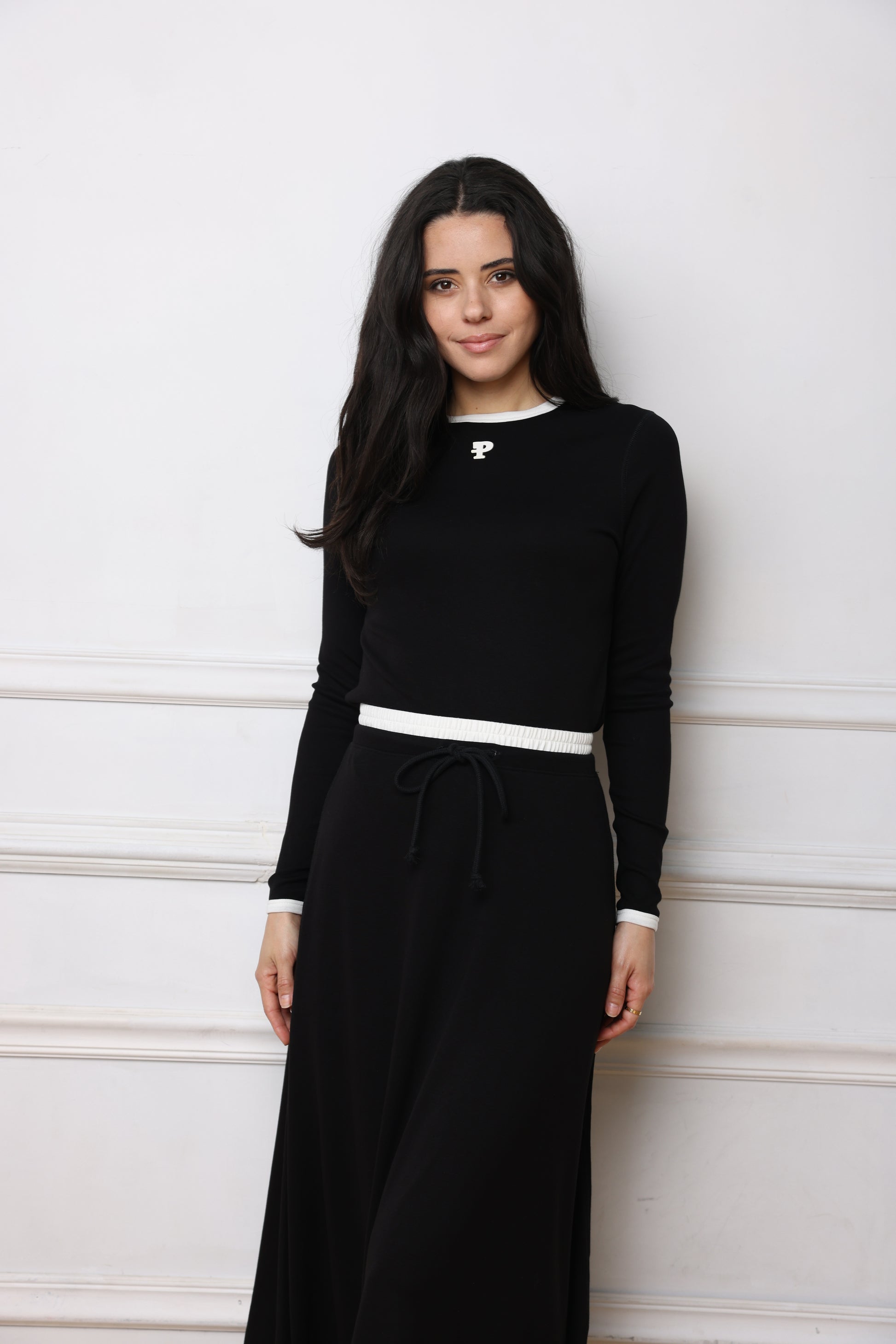 Woman wearing a black dress with white stripes on a white wooden floor