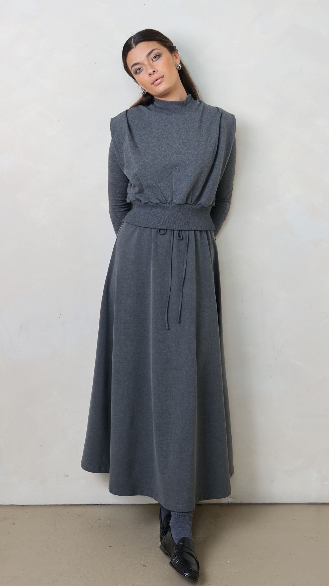 Woman wearing a long gray skirt against a white background