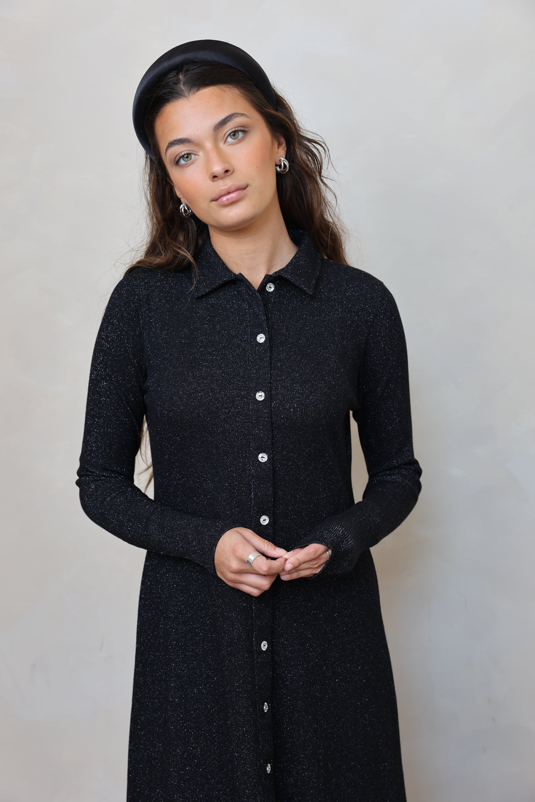 Woman wearing a black coat and cap on a plain background