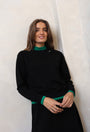Woman wearing a black outfit with green accents against a white background