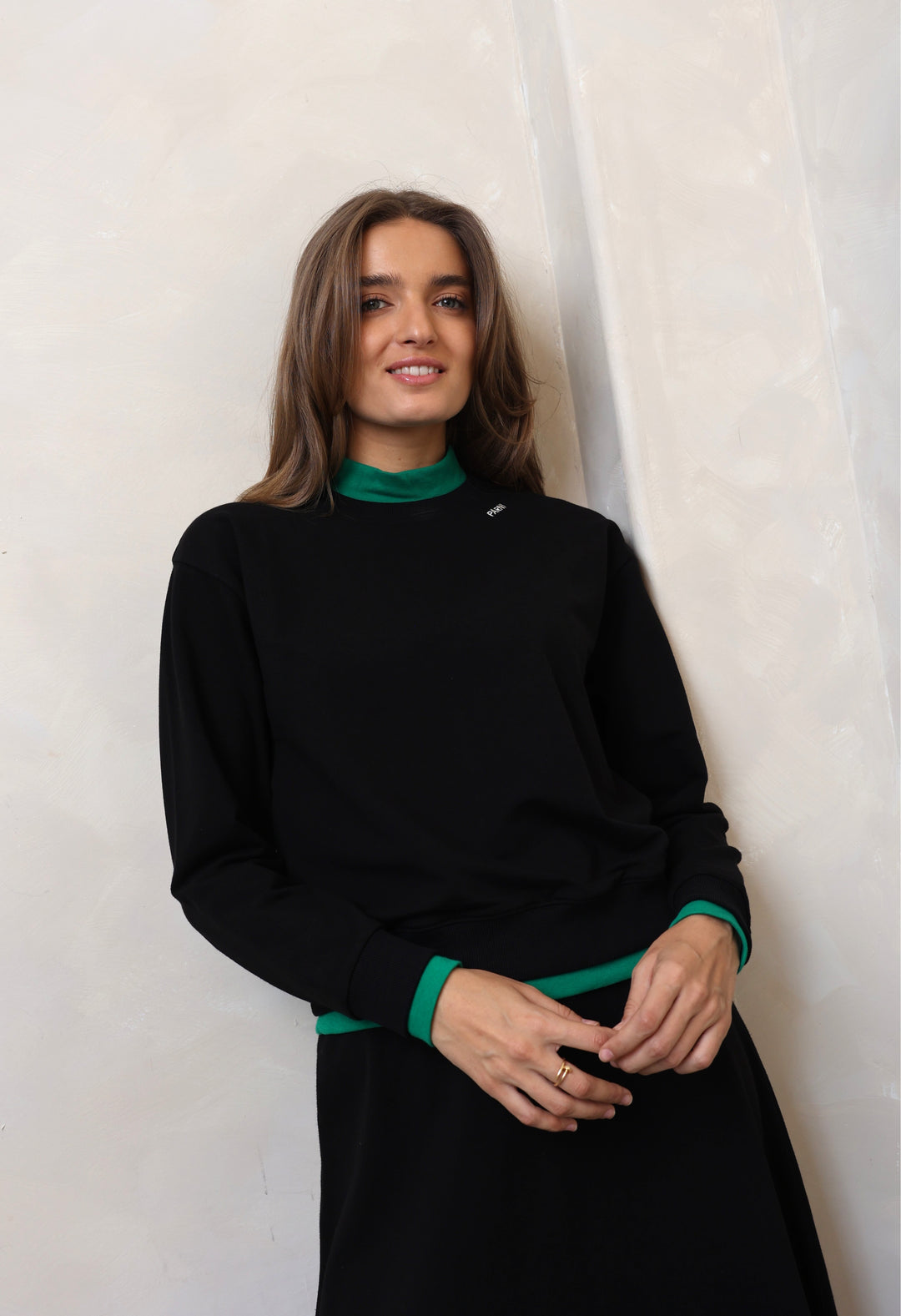 Woman wearing a black outfit with green accents against a white background