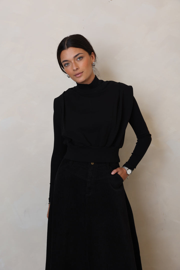 Person wearing a black outfit on a plain background