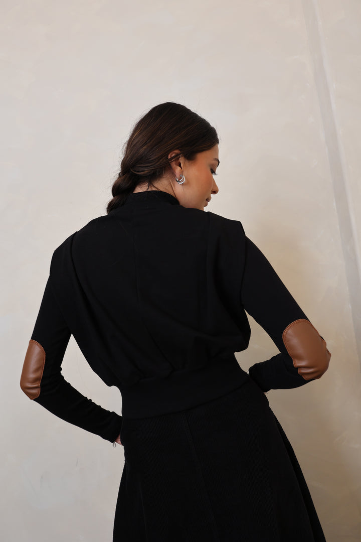 Person wearing a black dress with long sleeves on a plain background