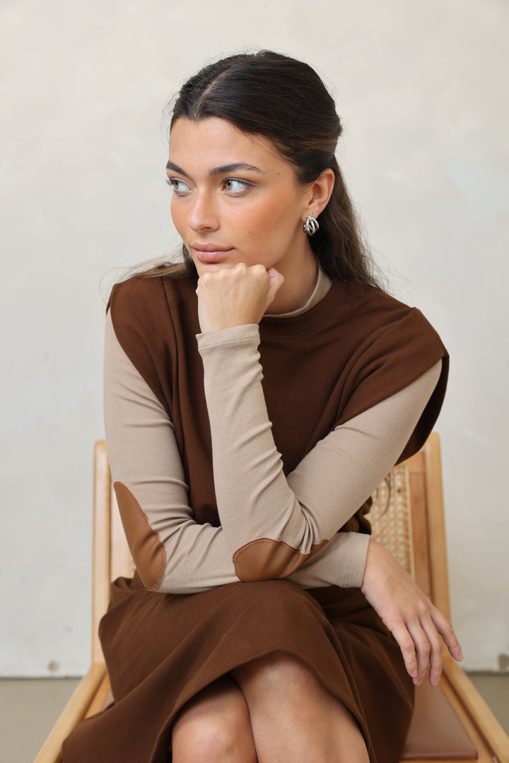 Woman wearing a brown and beige dress lying on a white surface