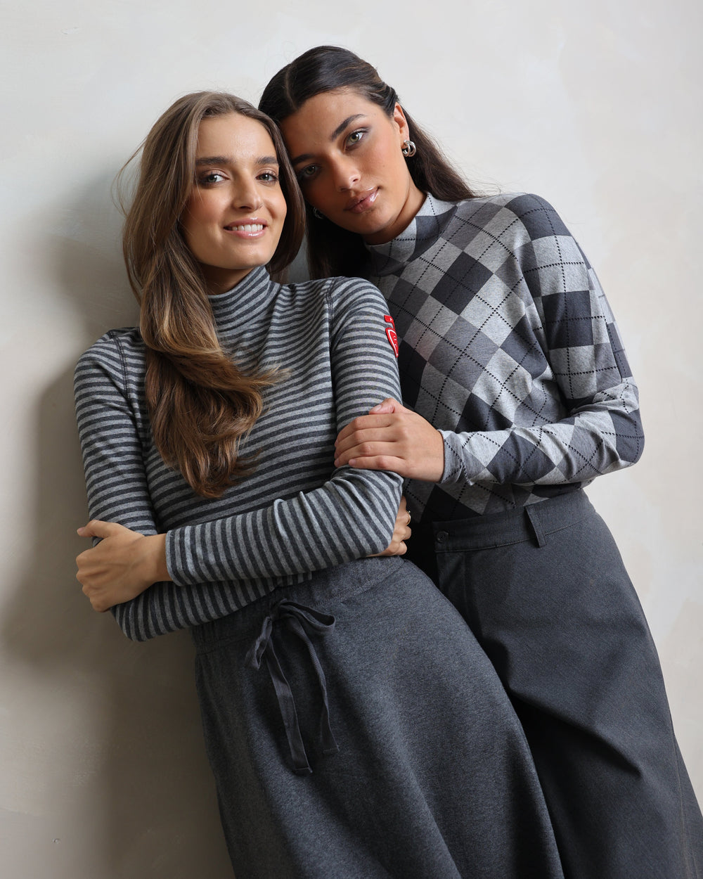 Two people wrapped in a blanket on a plain background
