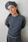 Person wearing a gray outfit and hat on a light background