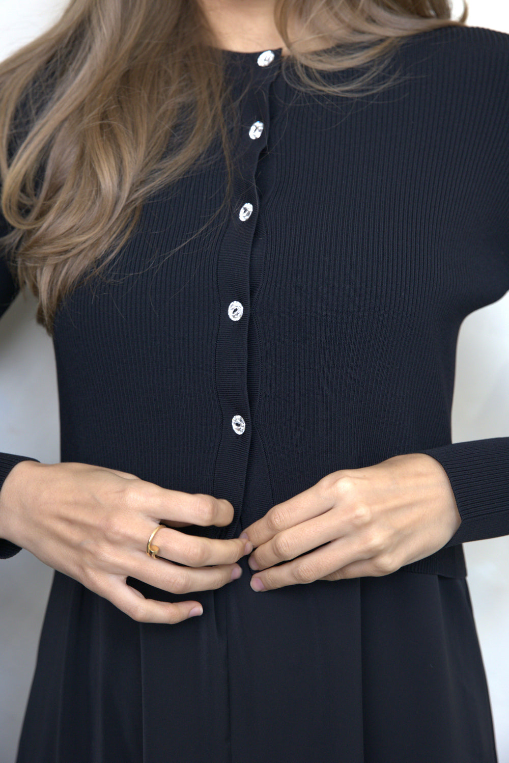 Woman buttoning a cardigan