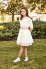 Young girl in a white dress standing on grass with trees in the background
