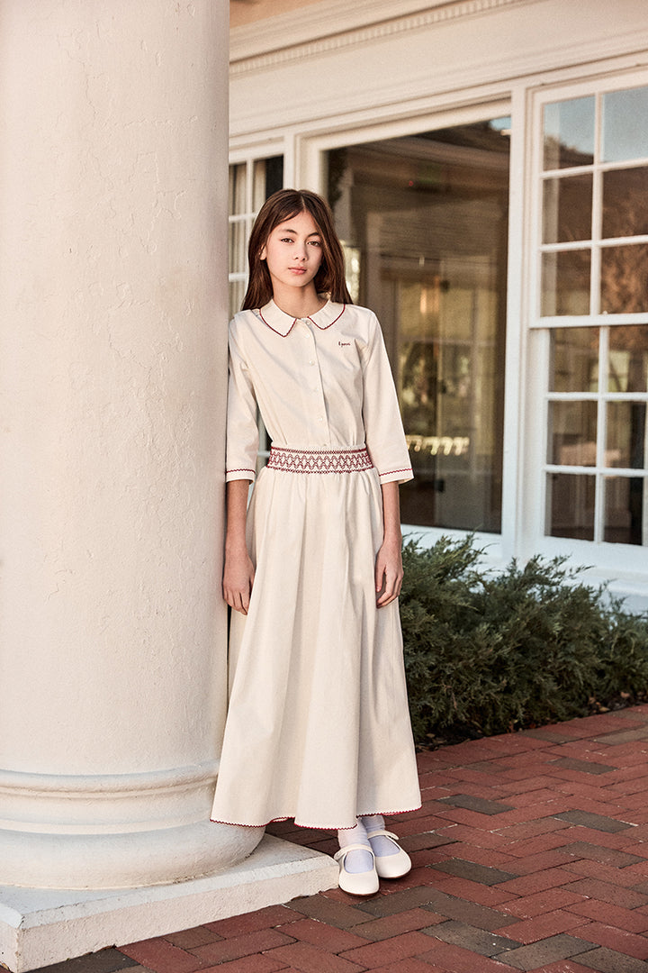 Woman in a white dress standing next to a building with columns.