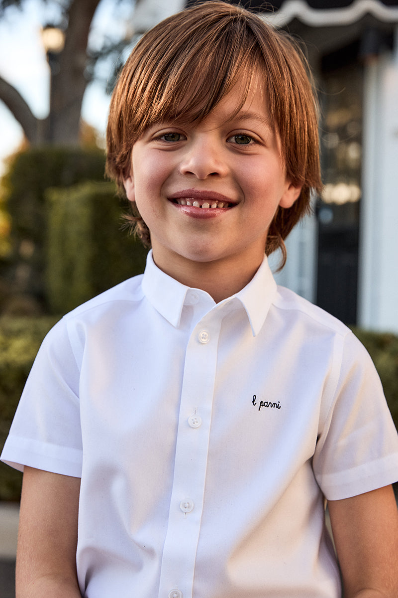 Child wearing a white shirt with a logo outdoors