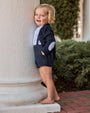 Child in a navy outfit standing on a stone step outdoors