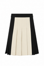 A pleated A-line skirt with a colorblock design, featuring a wide black waistband, a central cream-colored pleated panel, and black side panels, shown against a plain white background.