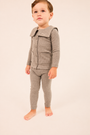 A toddler standing barefoot against a plain light beige studio background, wearing a matching heather gray knit outfit with a long-sleeve button-front top and leggings.
