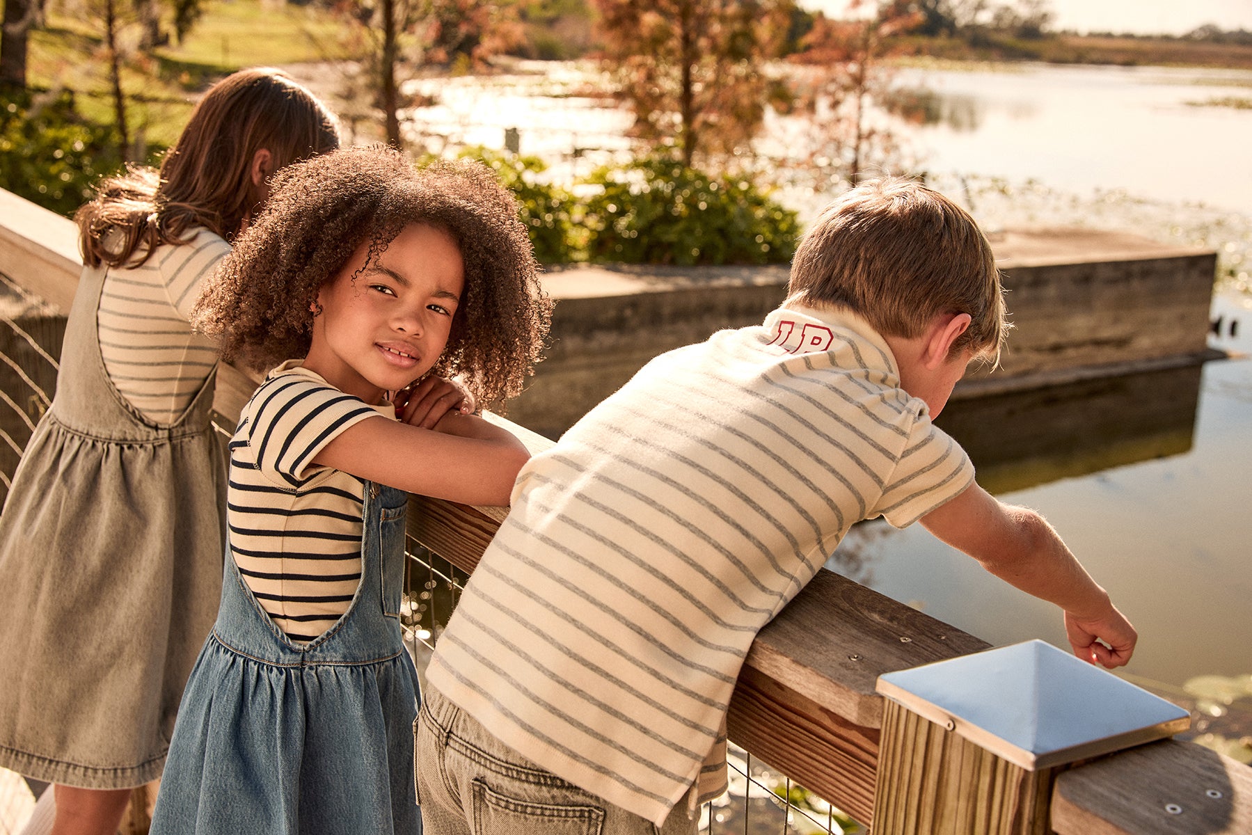 Children playing by a lake with a wooden dock