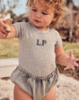 Baby wearing the Denim Baby Bloomers in Grey.