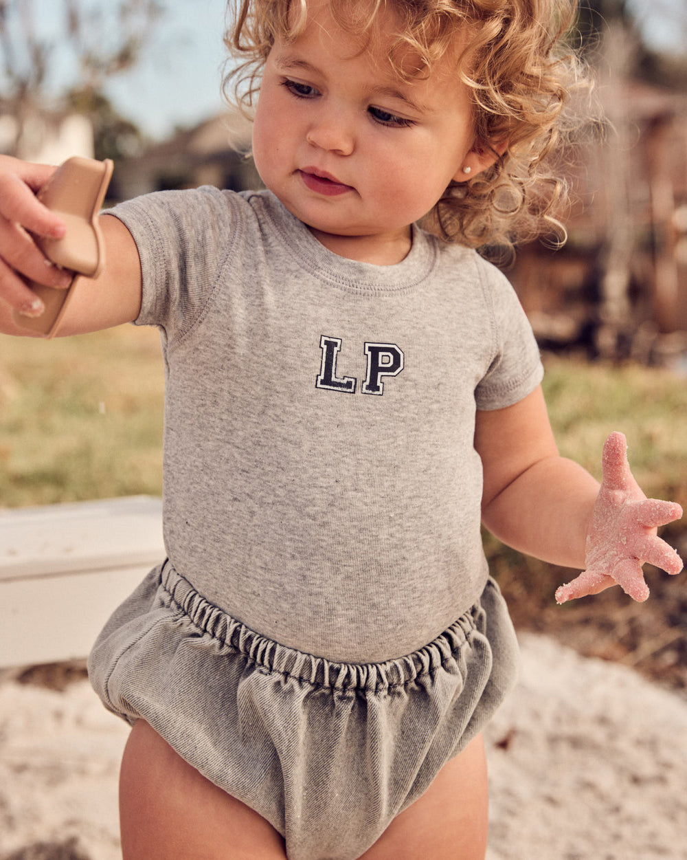 Baby wearing the Denim Baby Bloomers in Grey.