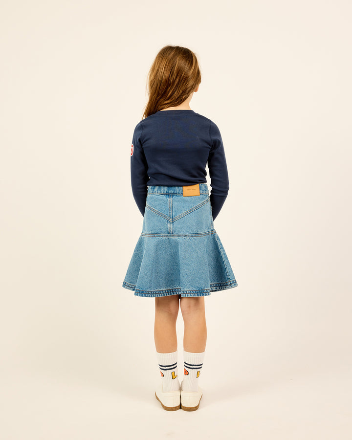 The backside of the model wearing the Short Ruffle Denim Skirt in Blue.