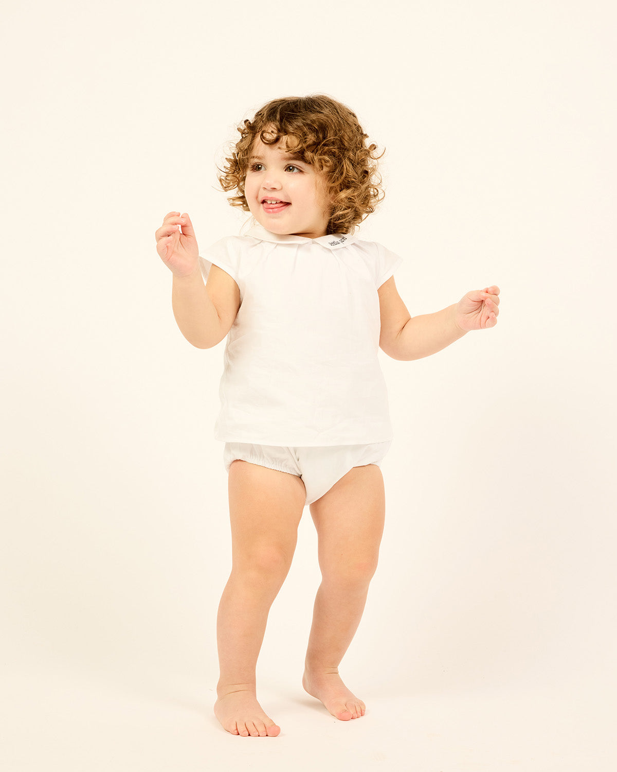 Baby wearing the Two-piece Cotton Set With Bloomers in white.