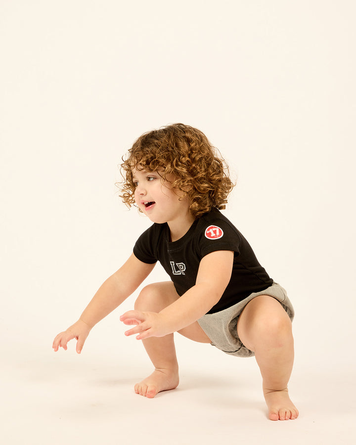 Baby wearing LP Est. 17 Baby Bodysuit in Black with denim bloomers.