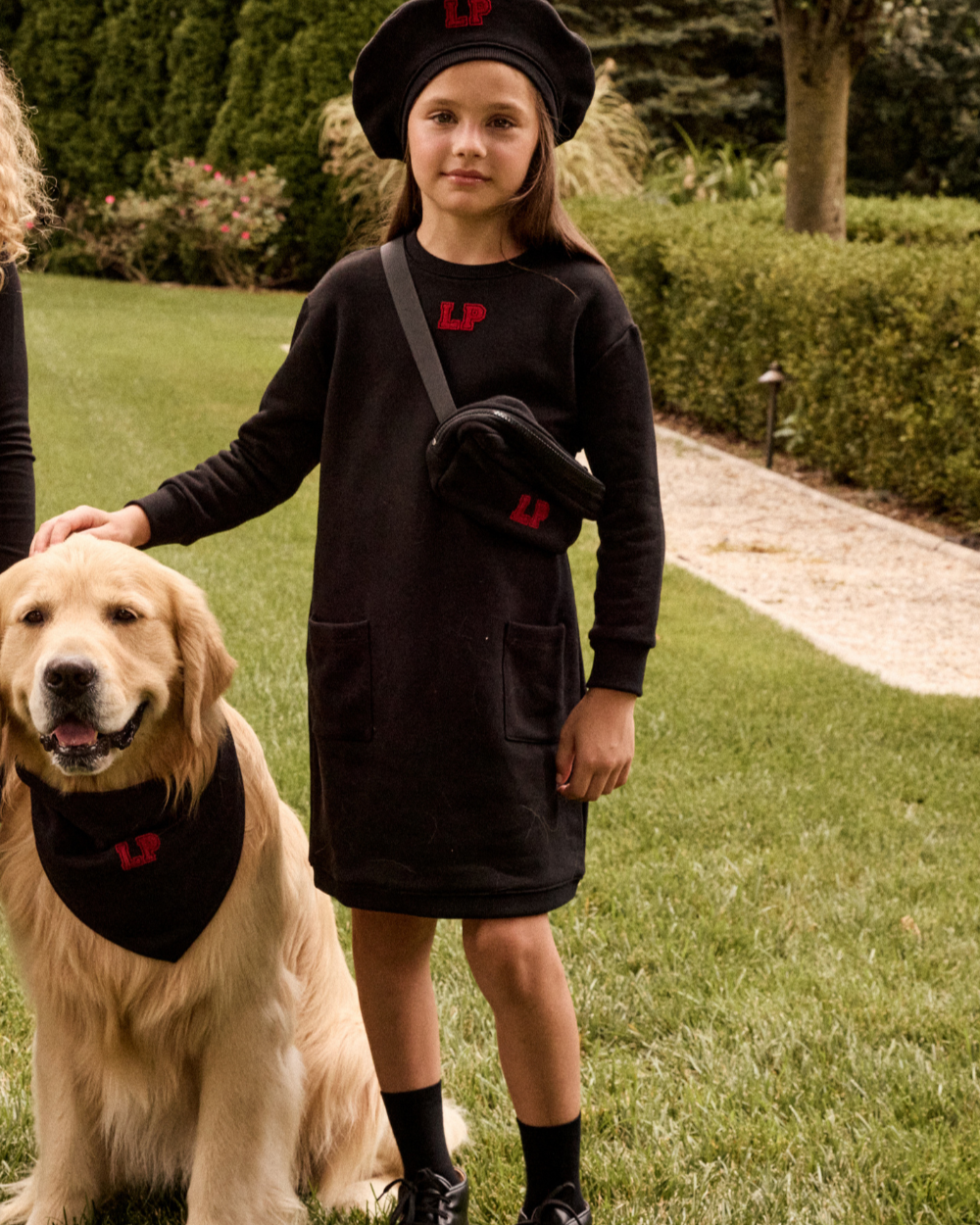 Young girl in a black outfit with a dog on a grassy lawn