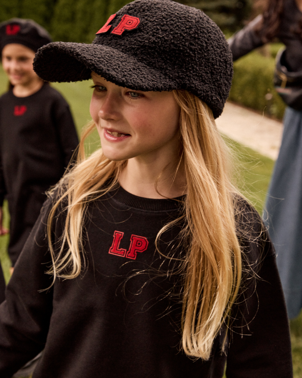 Person wearing a black cap and sweatshirt with 'LP' logo outdoors