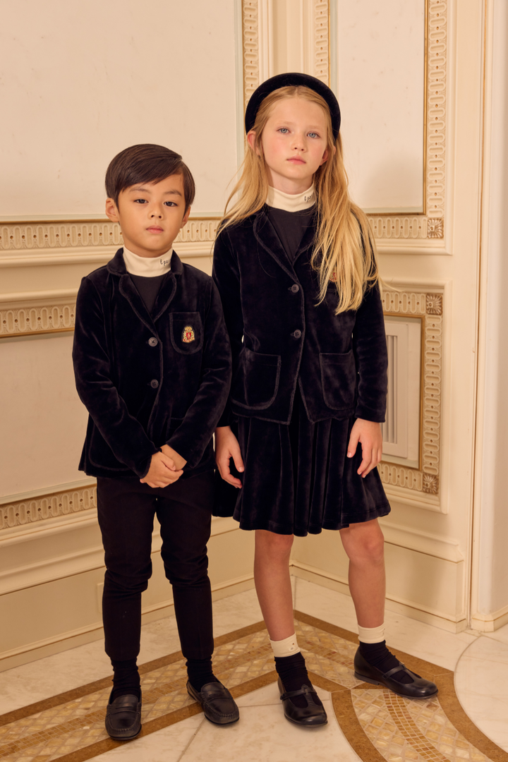 Two children in formal attire standing in a decorated room.