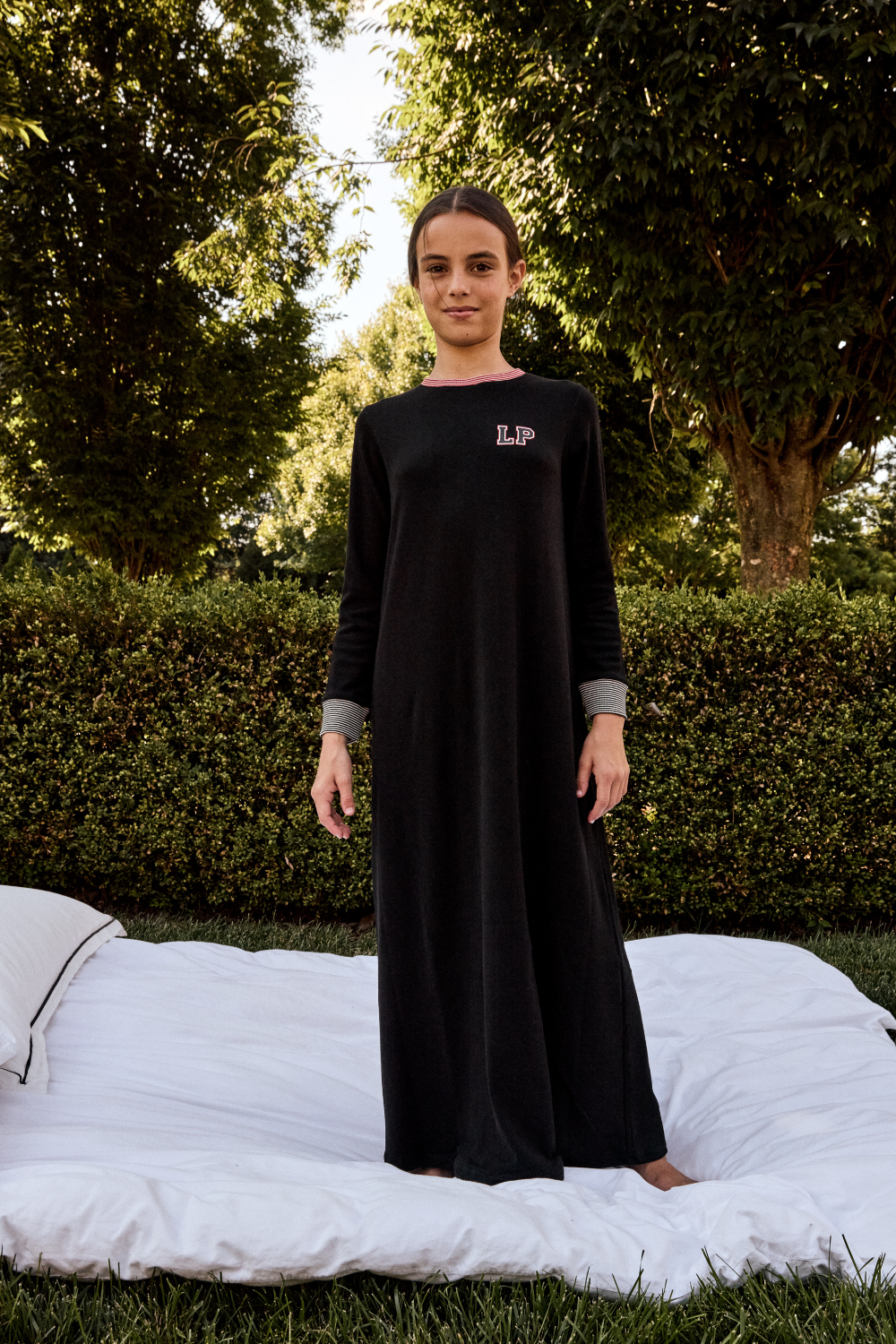 Person wearing a black dress with a logo in an outdoor setting