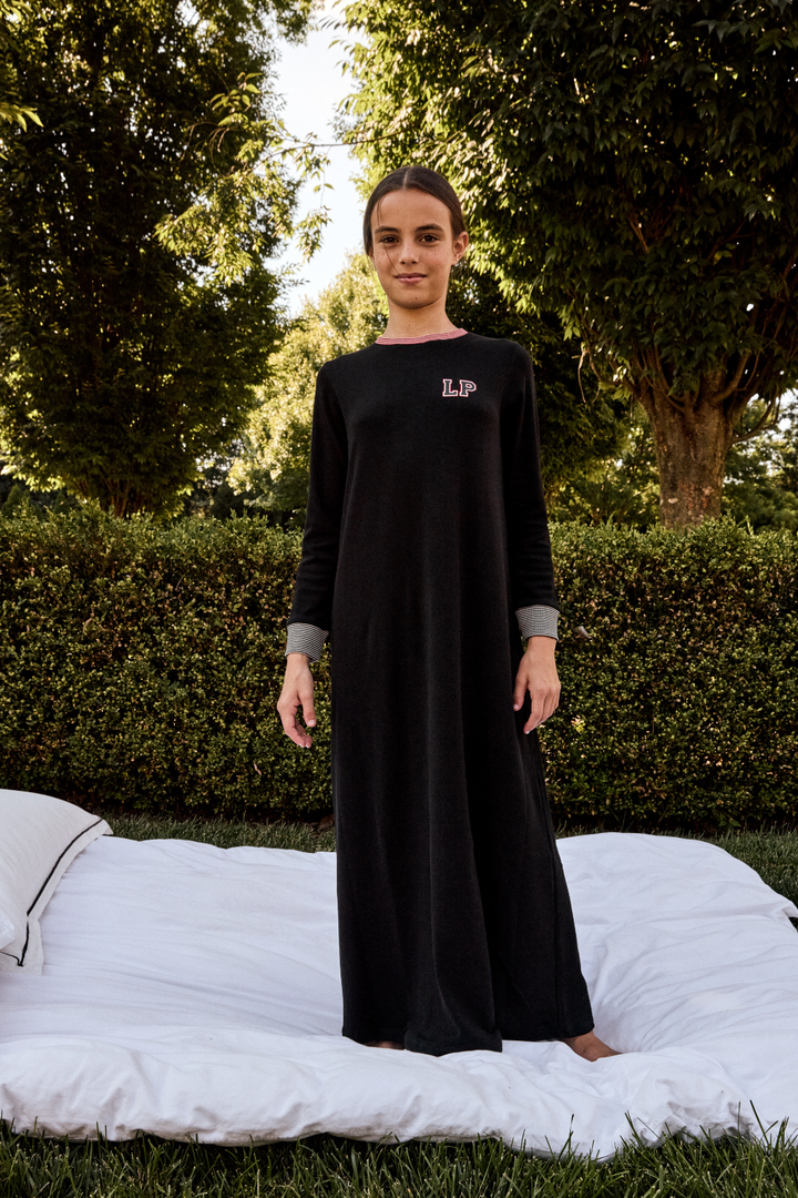 Person wearing a black dress with a logo in an outdoor setting