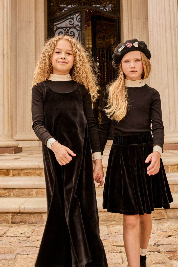 Two young girls in black outfits standing on stone steps.