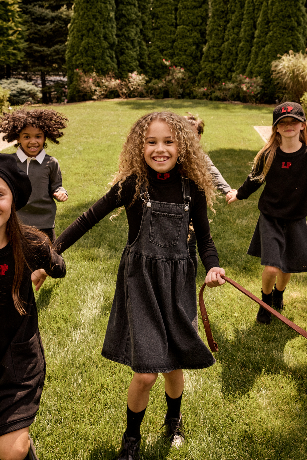 Children in Little Parni Denim playing outdoors on a grassy field.