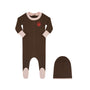A baby footed one-piece sleeper in dark brown with light pink cuffs and toe caps, featuring a small red heart logo on the chest, shown alongside a matching brown beanie hat on a white background.