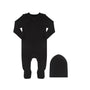 A black baby footed sleeper with long sleeves and a matching black beanie hat, displayed on a clean white background.