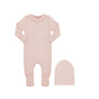 A baby's long-sleeve footed sleeper in a soft dusty pink color, shown next to a matching knit bonnet on a plain white background.
