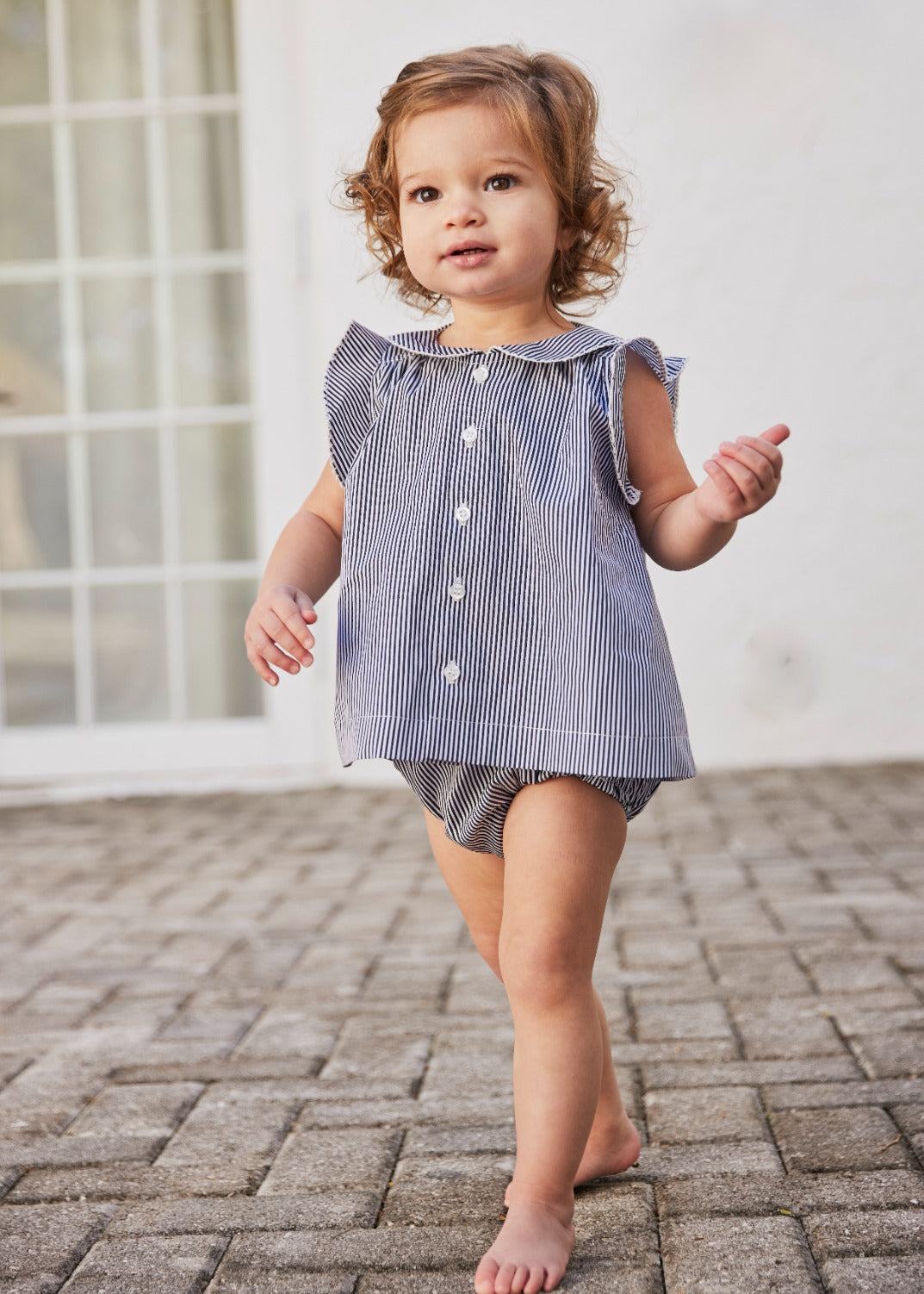 Little girl wearing the Baby Striped Ruffle Tunic & Bloomer Set in black and white stripe