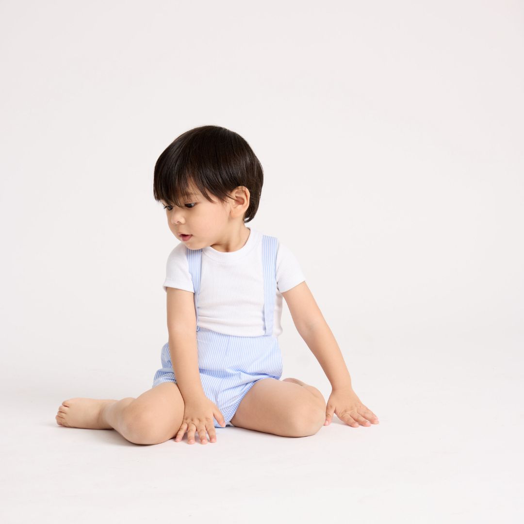 Little boy wearing blue and white striped baby shorts with a short sleeve white tee