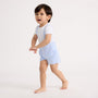 Little boy standing wearing the blue and white striped shorts overalls with a white tee