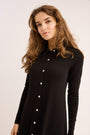 Woman wearing a black button-up shirt against a plain background