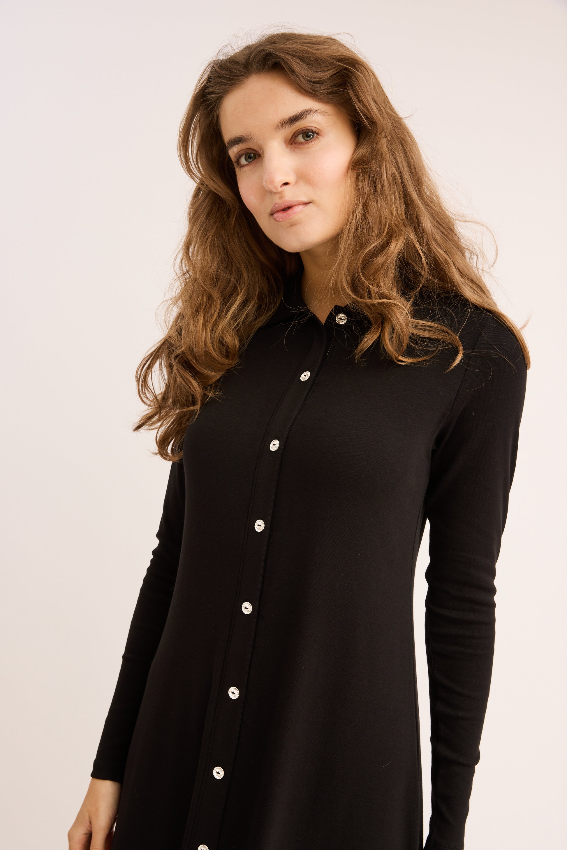 Woman wearing a black button-up shirt against a plain background