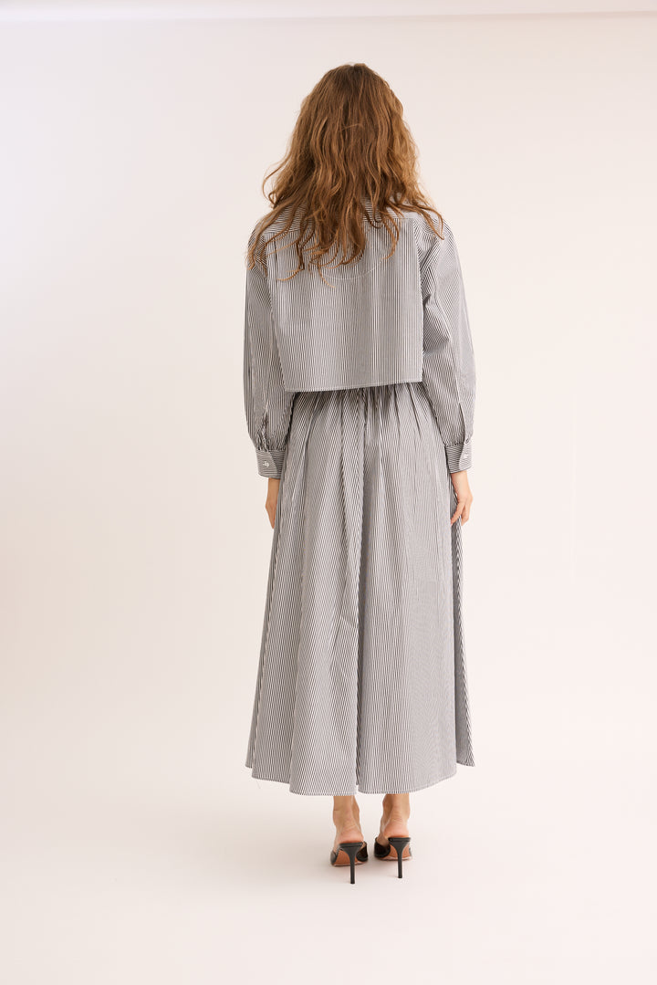 Model turned to show the back of the Striped Poplin Cropped Shirt and skirt.