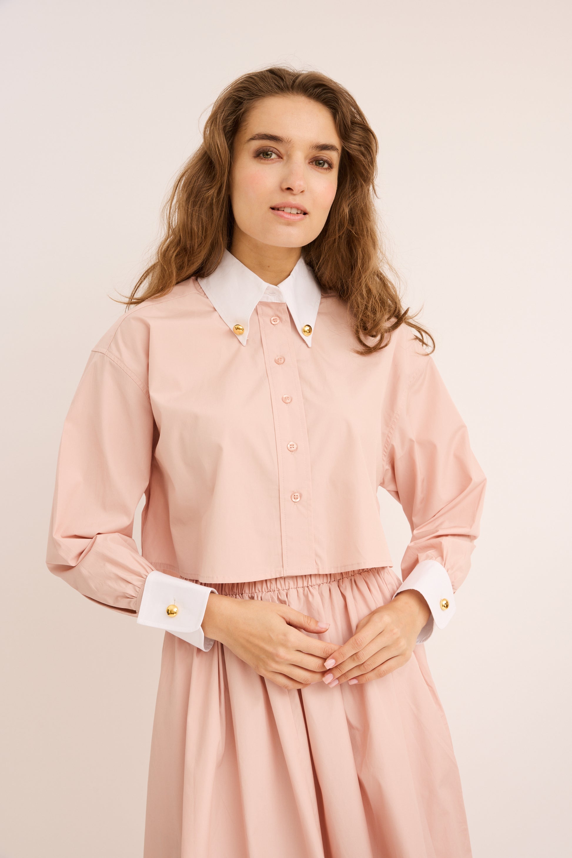 Woman wearing the blush Cropped Poplin Contrast Collar Shirt with matching skirt. 
