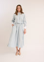 Woman wearing the light blue Cropped Poplin Contrast Collar Shirt with matching skirt. 