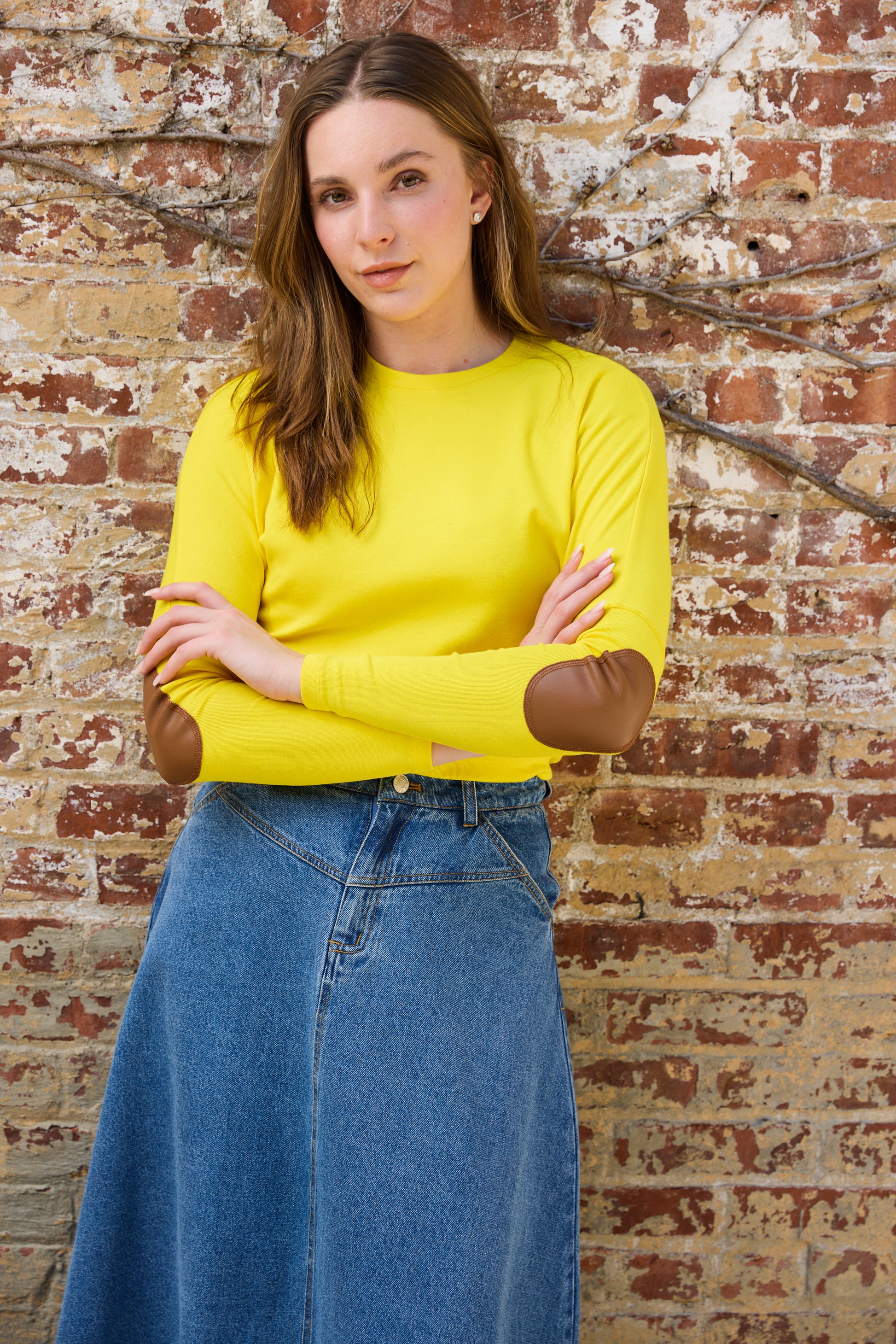 Woman wearing the yellow Elbow Patch Dolman Tee with Denim skirt. 