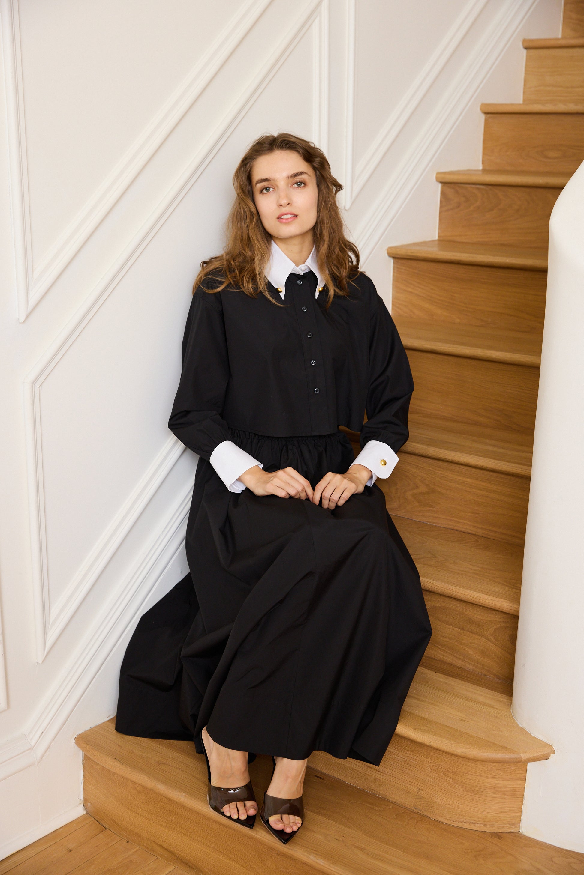 Woman wearing the black Cropped Poplin Contrast Collar Shirt with matching skirt. 
