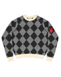 A knit crewneck sweater by A'NANI, featuring a black and gray argyle pattern with cream ribbed collar, cuffs, and hem, and a red shield patch on the left sleeve.