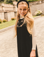 A girl wearing a long sleeve black mock turtleneck top with a contrasting ivory collar, standing outdoors.